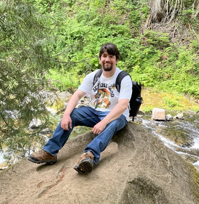 Anthony Navarro sitting on a rock near a waterfall